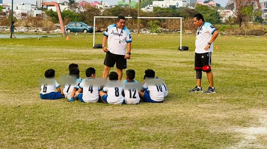 Entrenador dando indicaciones a los niños del equipo durante la práctica